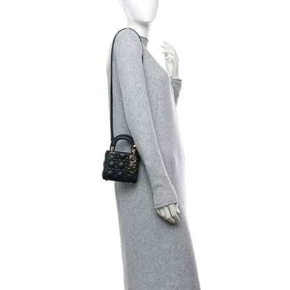 Black leather micro handbag with gold-tone charm on shoulder strap
