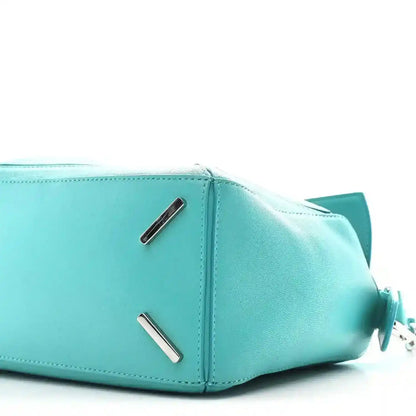 Teal-blue small Puzzle bag side view with metal bar accents and zip opening edge.
