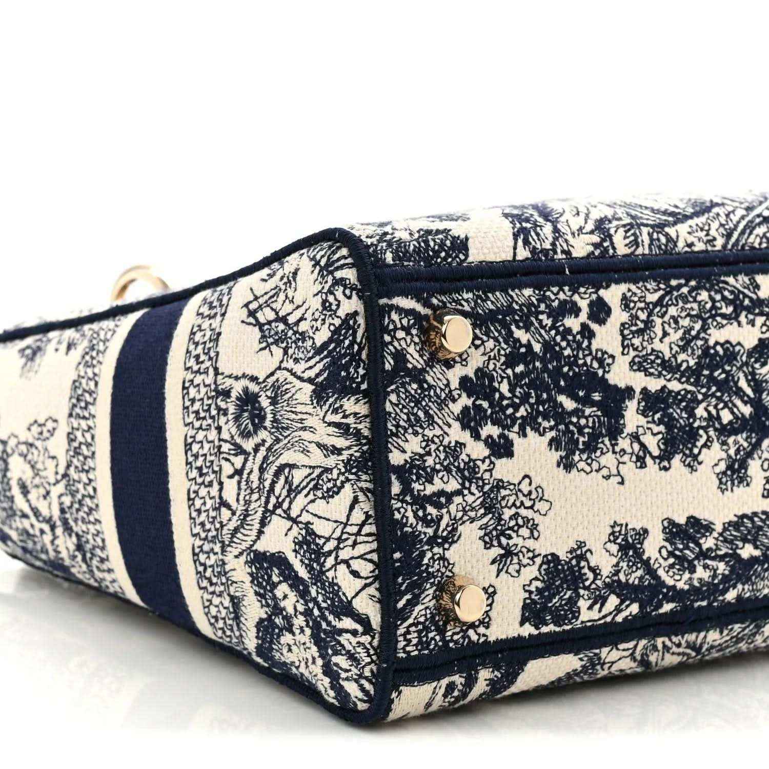 Blue toile de Jouy handbag base close-up showing navy trim and stitched side panel.