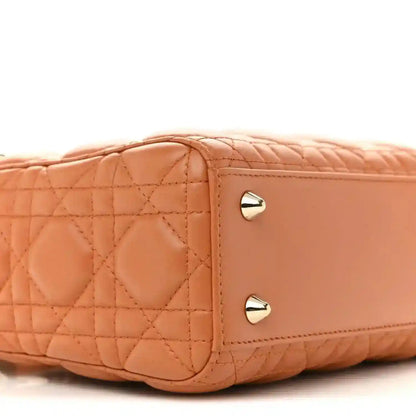 Side panel close-up of orange quilted Lady Dior tote with gold turn-lock studs