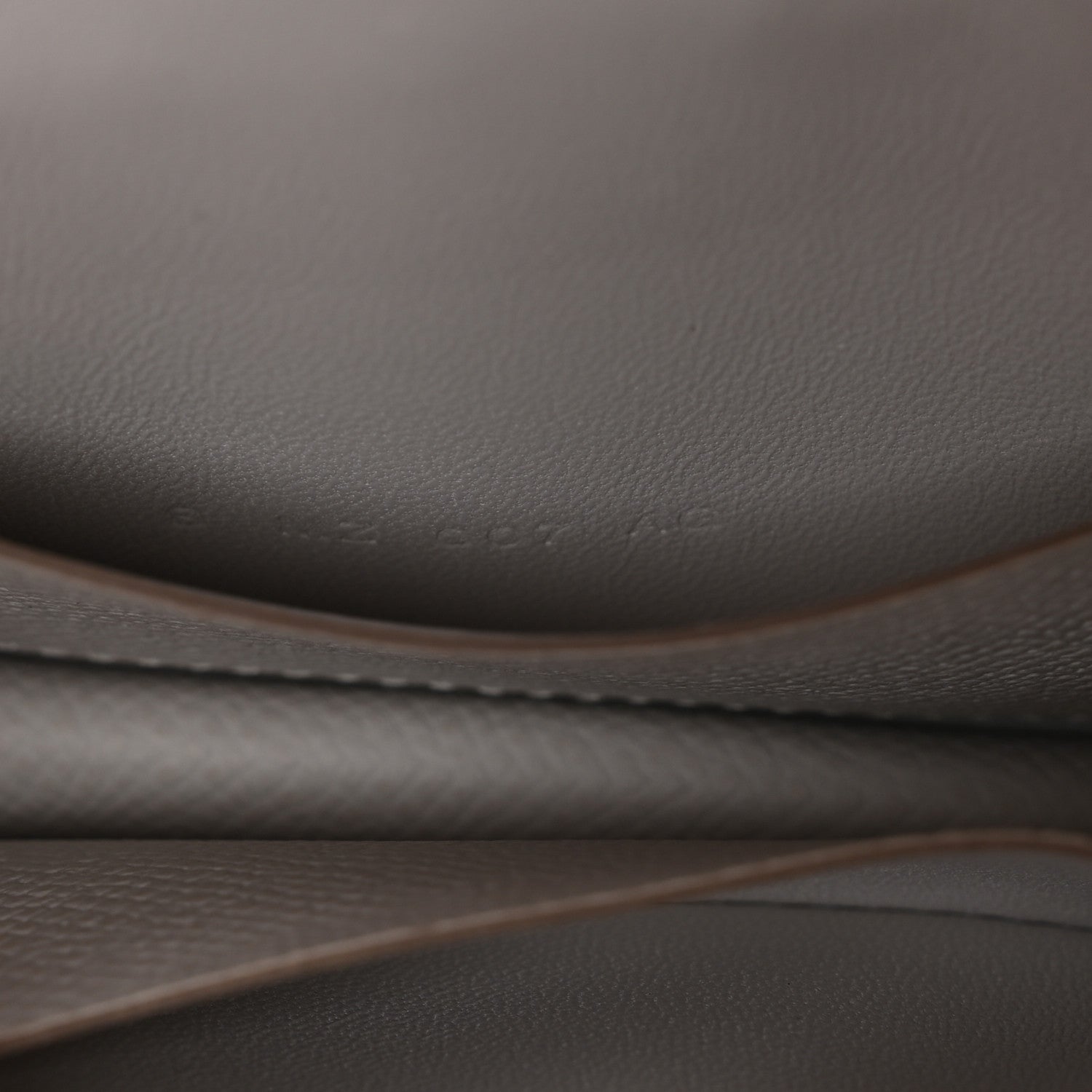 Pale gray leather edge and stitching detail on a slim wallet.