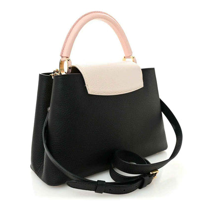 Black leather handbag with light cream top panel, pink handle, and black shoulder strap