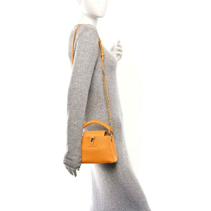 Yellow Mini Capucines handbag on a mannequin with short chain strap