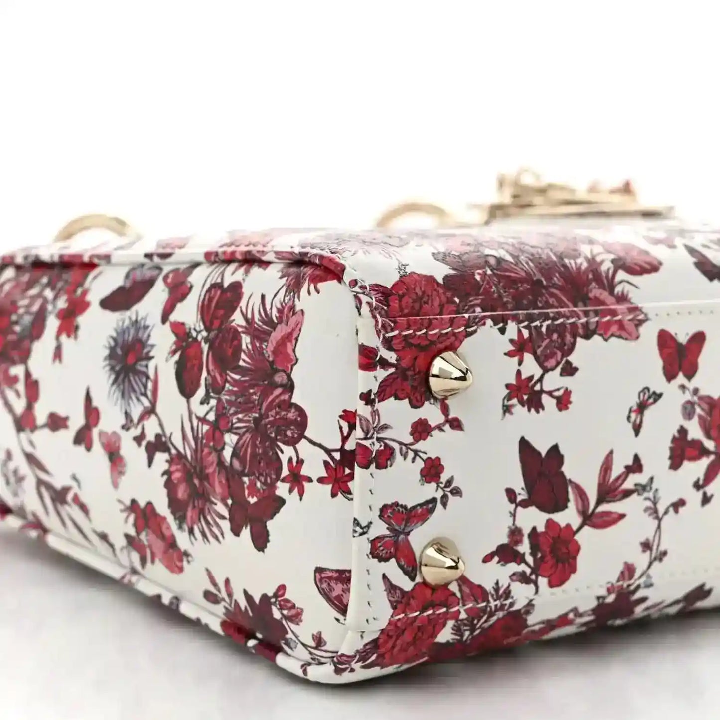 Small floral handbag with gold snap hardware and red-and-white fabric across the flap