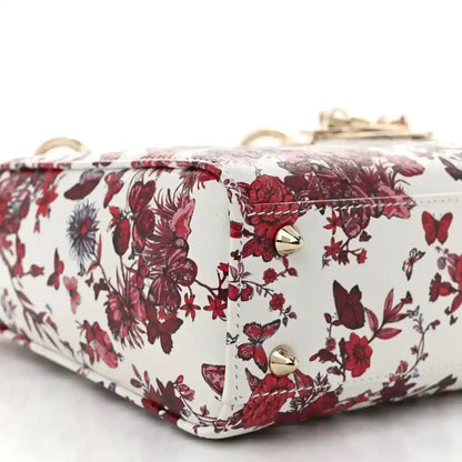 Small floral handbag with gold snap hardware and red-and-white fabric across the flap