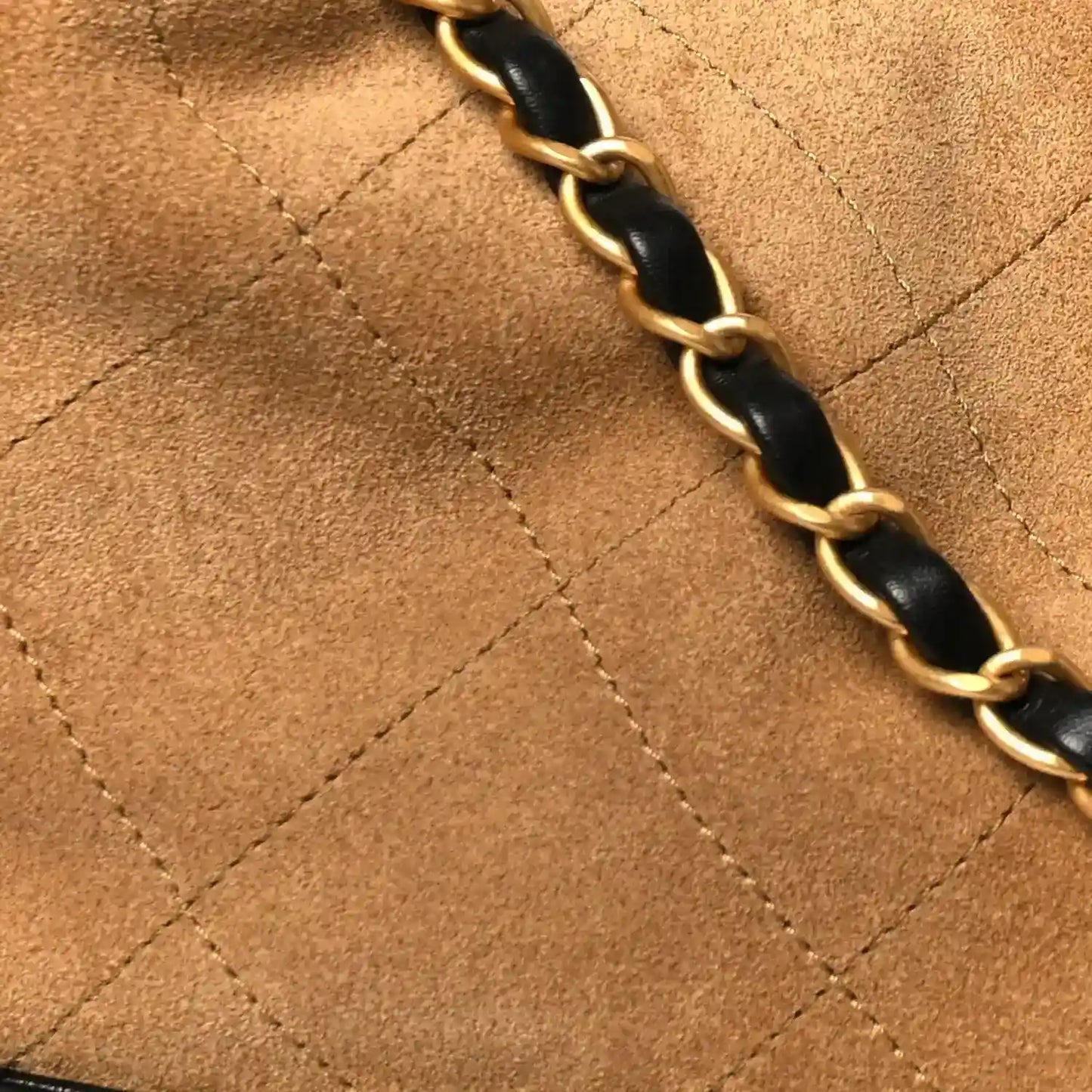 Beige suede panel with quilted stitching and black-and-gold chain strap