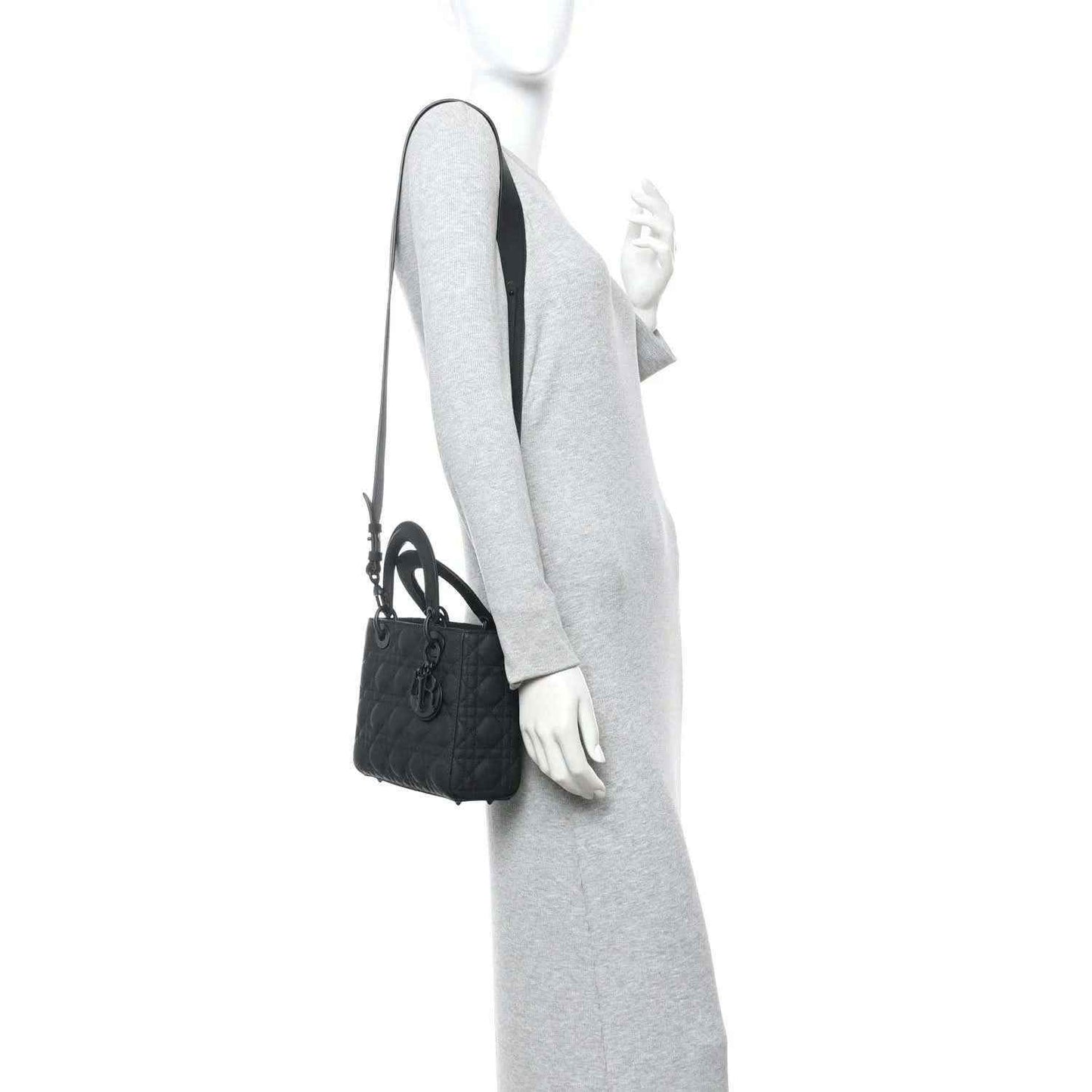 Black quilted handbag with top handle and shoulder strap shown on a model