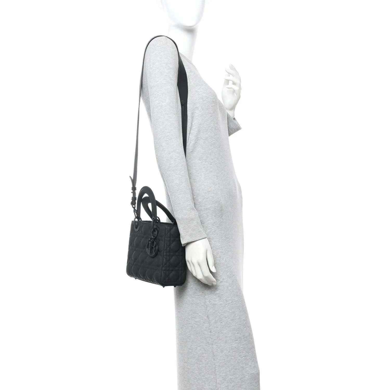 Black quilted handbag with top handle and shoulder strap shown on a model