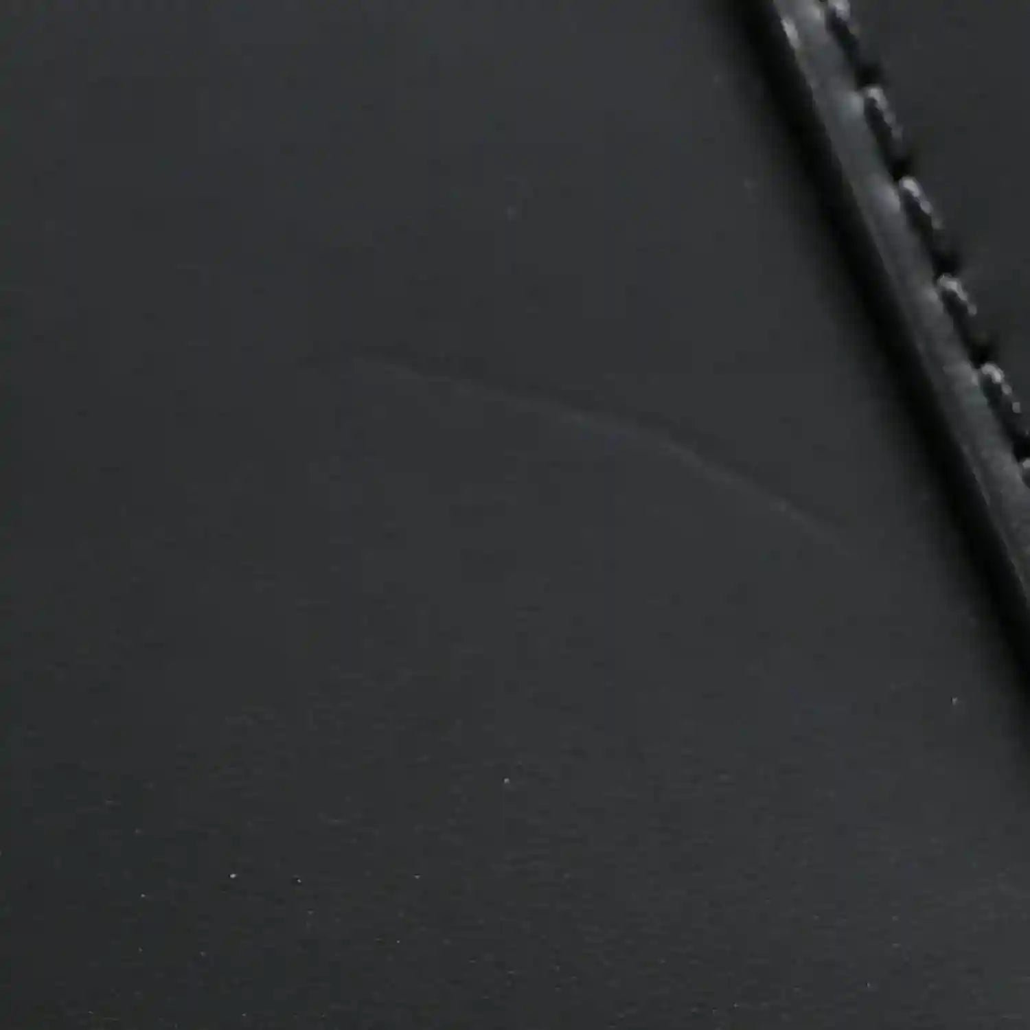 Black textured leather handbag with stitched edge and dark trim