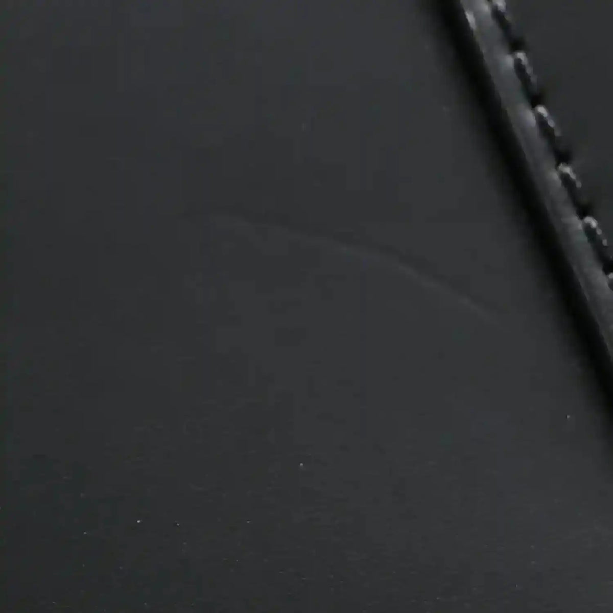 Black textured leather handbag with stitched edge and dark trim