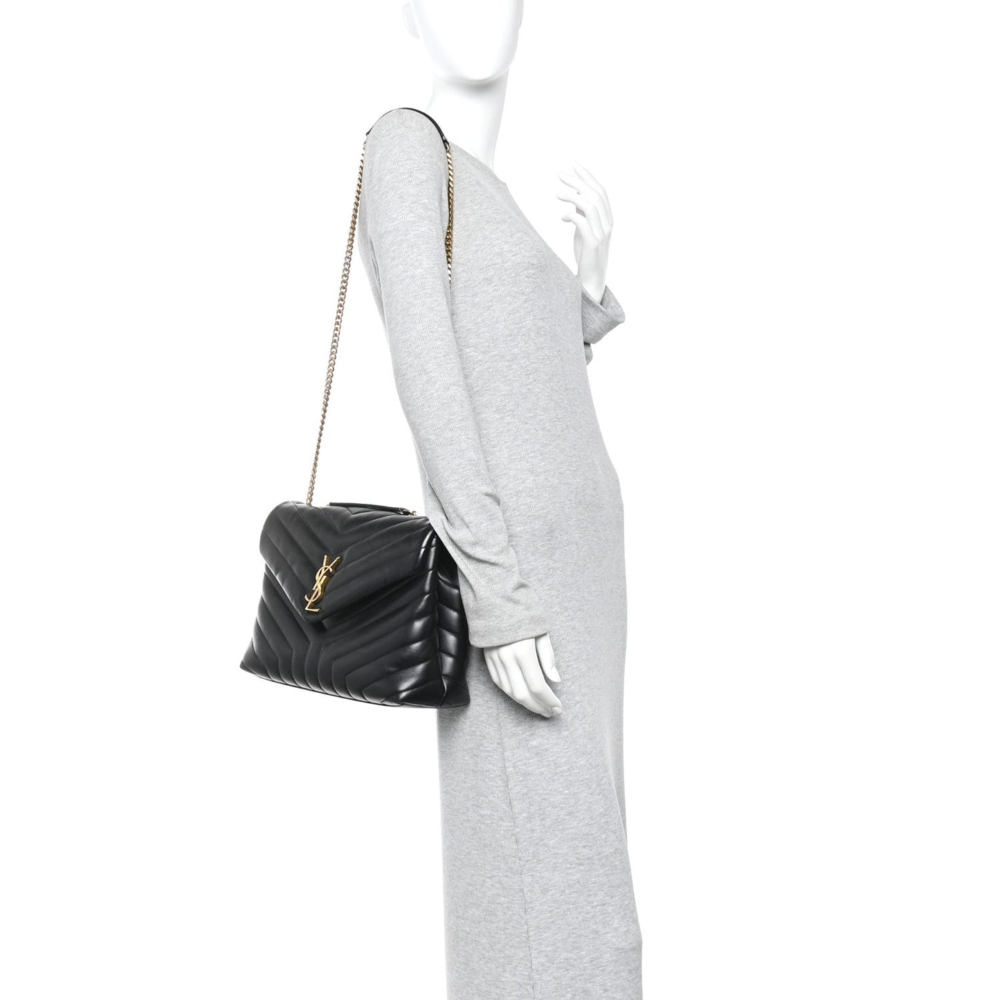Black quilted satchel with gold chain strap, held at side.
