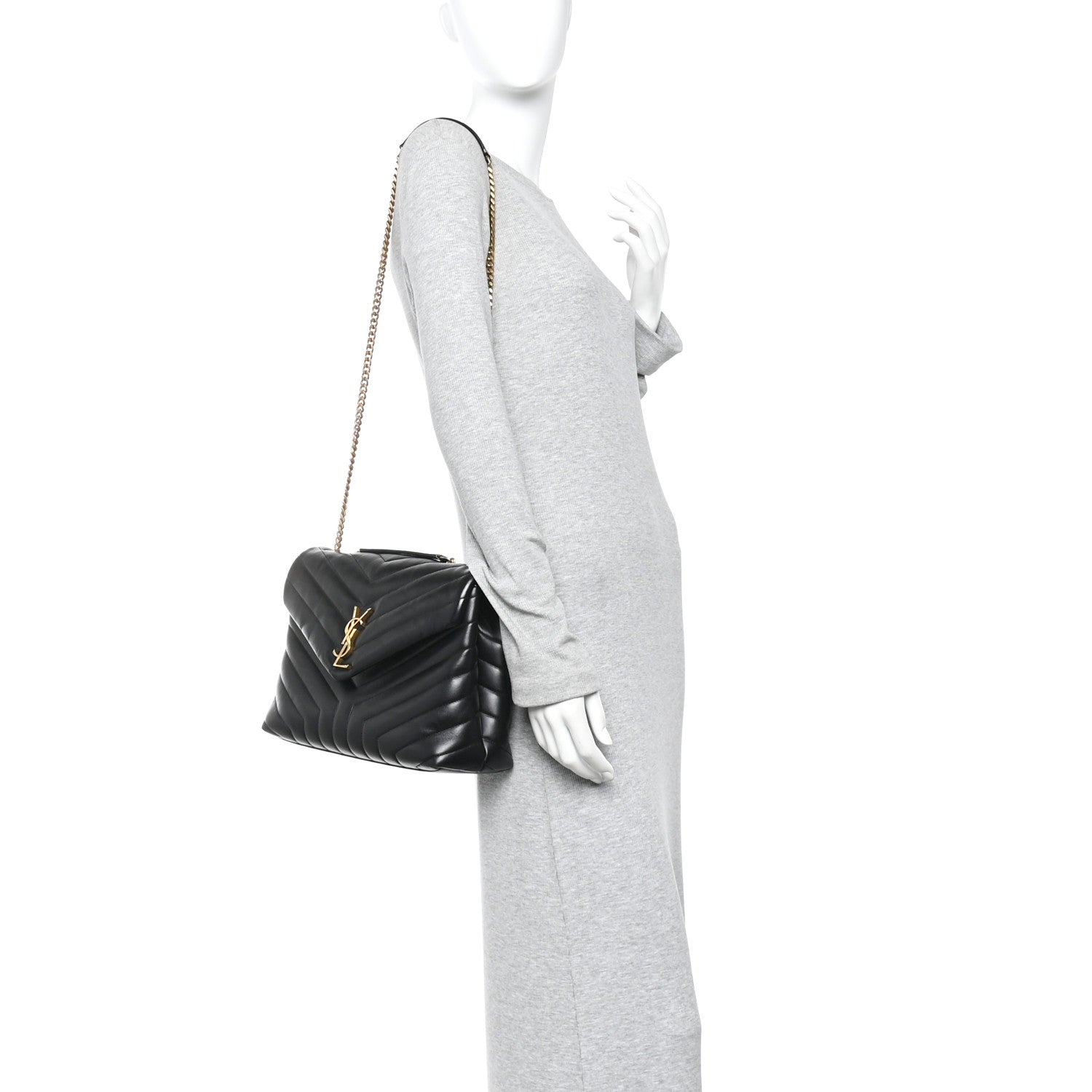 Black quilted satchel with gold chain strap, held at side.