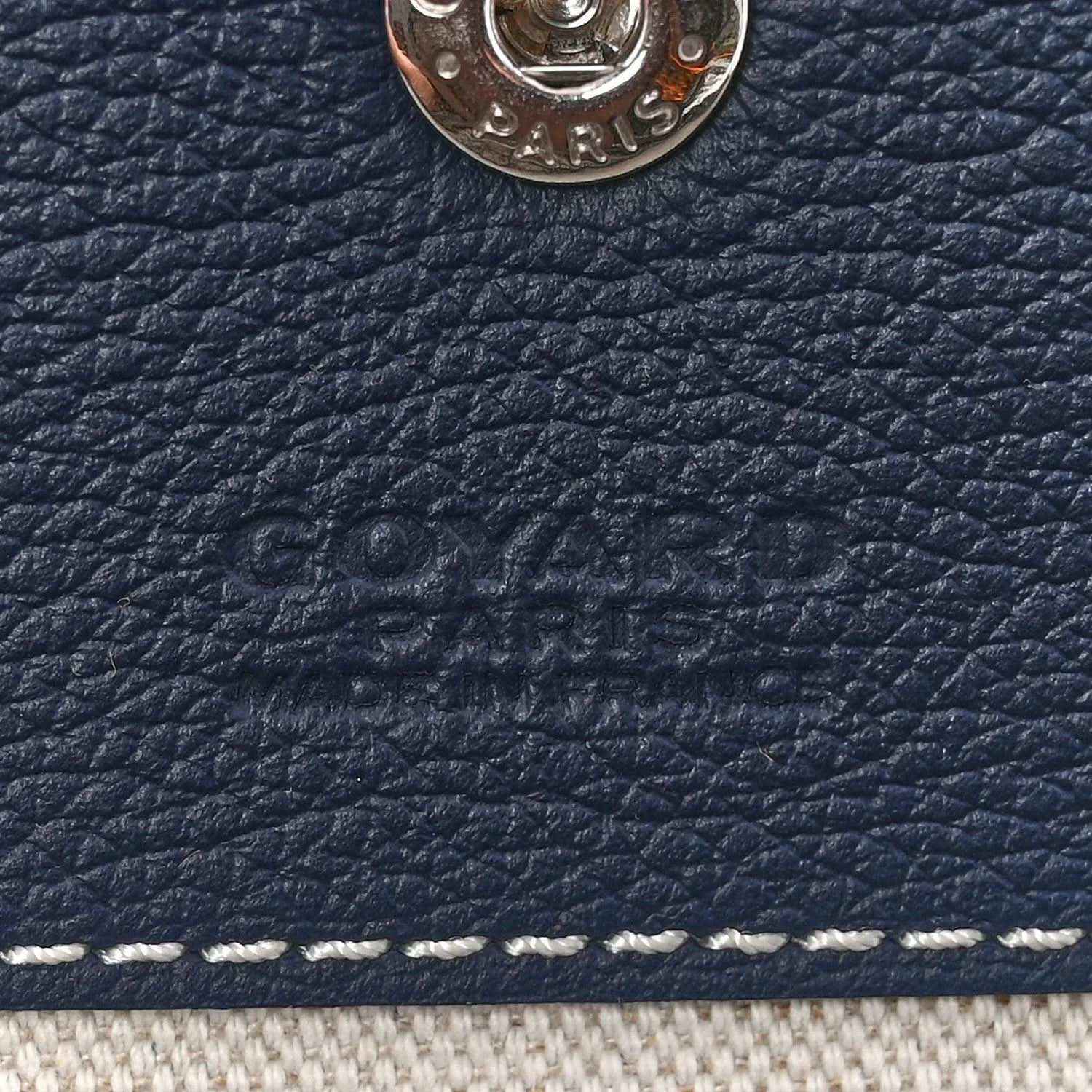 Close-up of navy pebbled leather trim with embossed Goyardine logo detail.