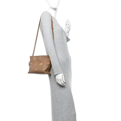 Tan mini crossbody clutch with knotted shoulder strap and compact top fold shape.