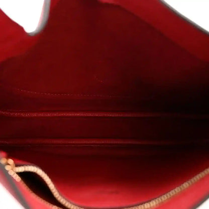 Red leather bag interior with lining and gold-toned chain detail near opening