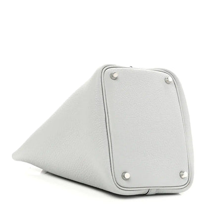 Light blue pebbled leather bucket bag side panel with metal studs and curved base