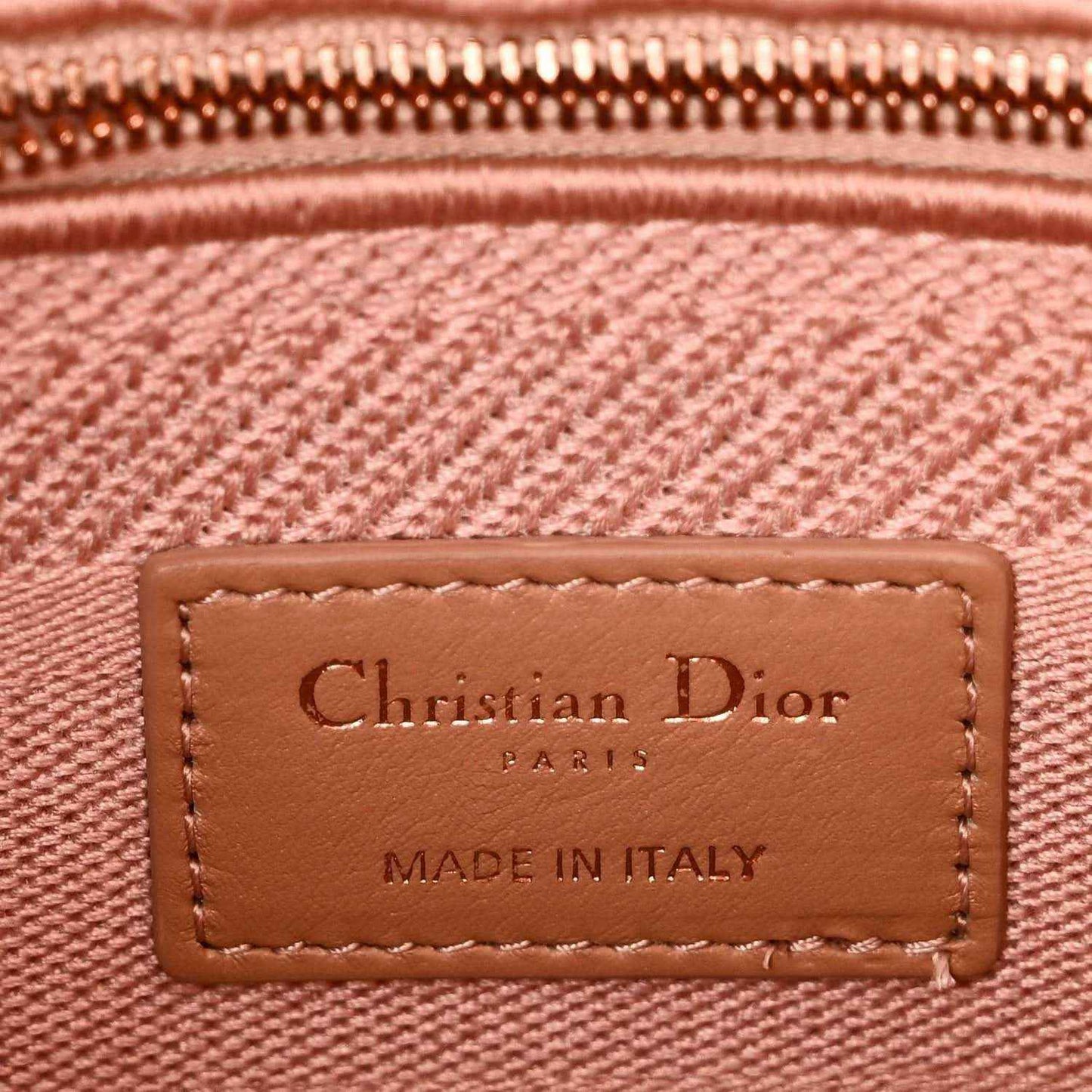 Leather logo label on pink canvas bag reading “Christian Dior” and “Made in Italy”