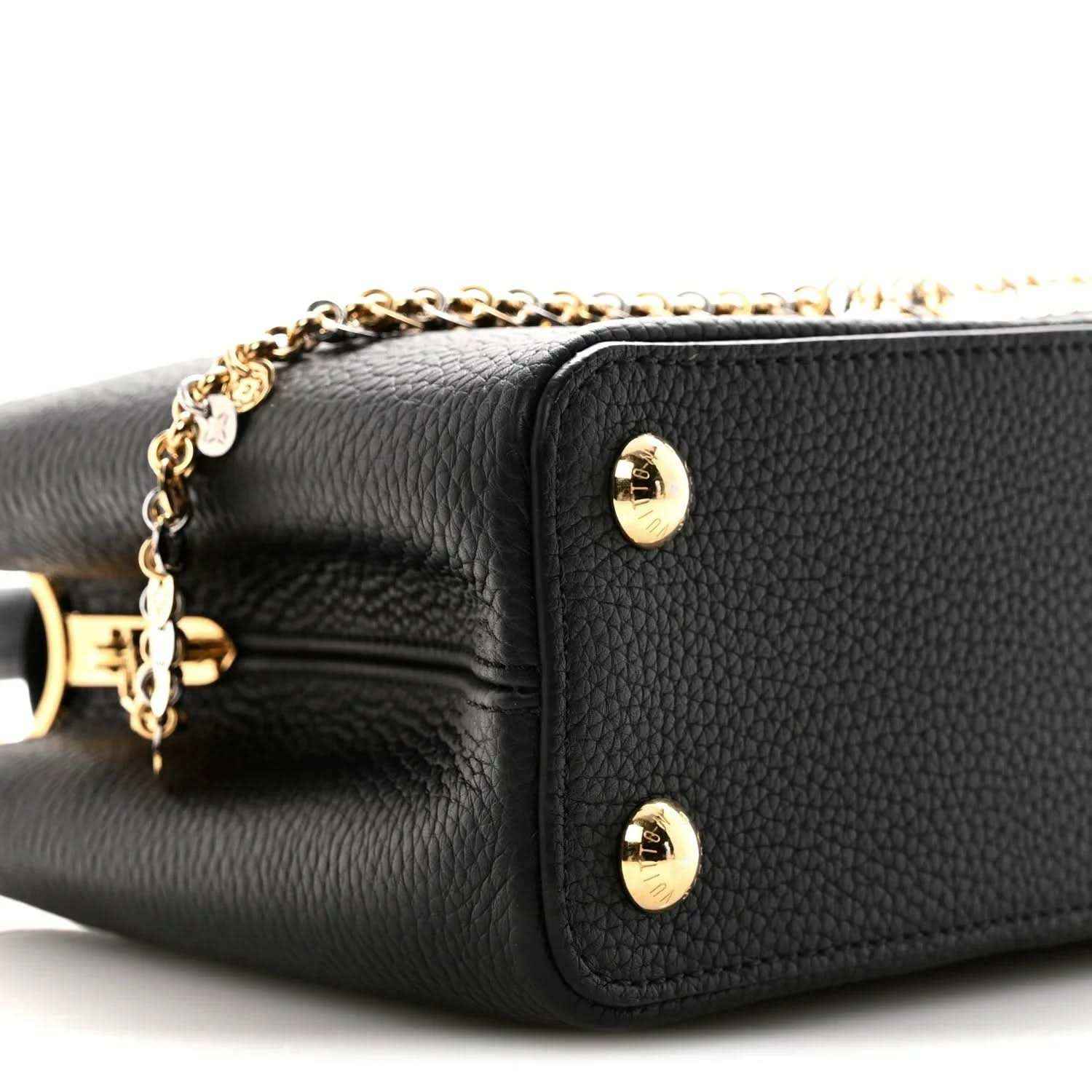 Black leather handbag side panel with two gold snap studs and chain detail
