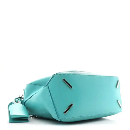Teal-blue small Puzzle bag with top zip hardware and two strap loop details.