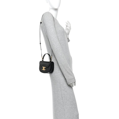 Black mini crossbody bag with short strap and gold-tone logo on front