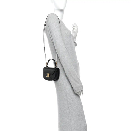 Black mini crossbody bag with short strap and gold-tone logo on front
