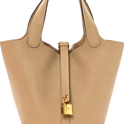 Beige leather tote with top handles and gold lock bar closure detail
