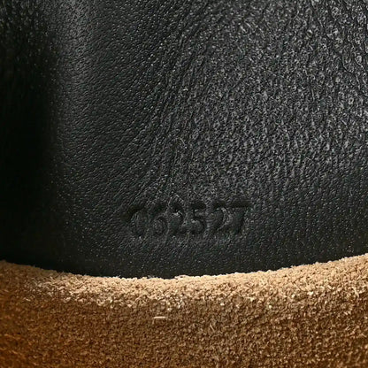 Black leather clutch surface with embossed code marking near the base seam