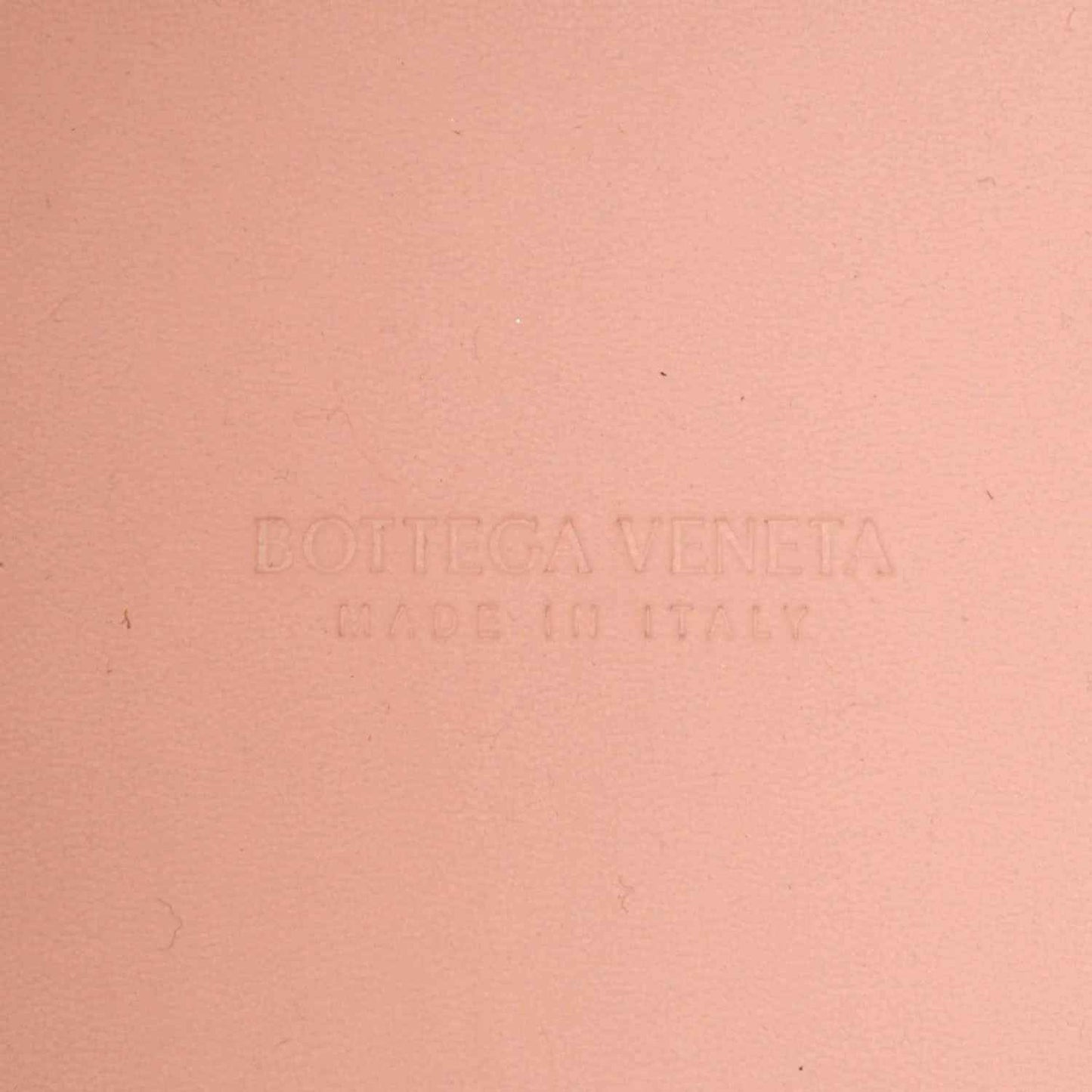 Pink leather bag surface with embossed Bottega Veneta logo