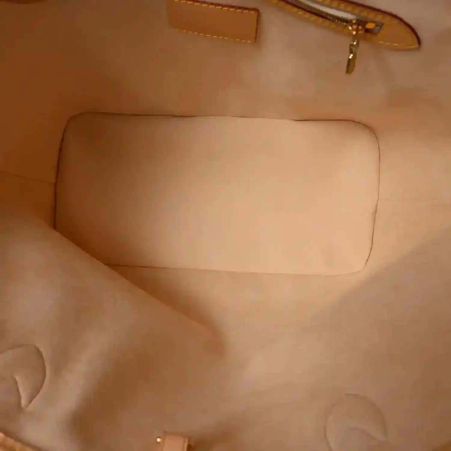 Beige fabric interior panel with stitched seams inside a zip pouch