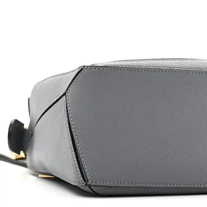 Small puzzle bag side view in dark gray leather with contrast edge stitching and base