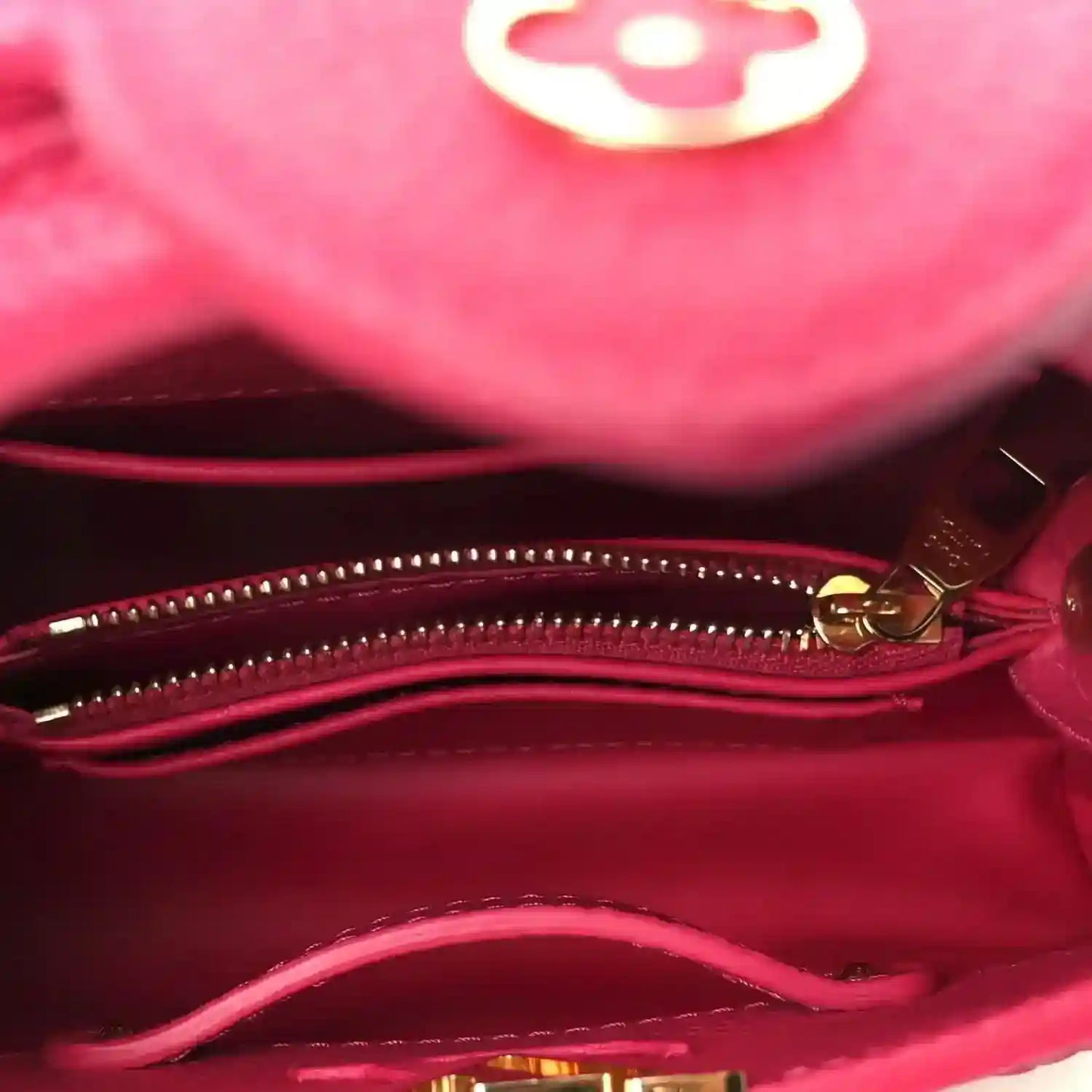 Magenta handbag interior with zip closure and gold zipper pull, close-up