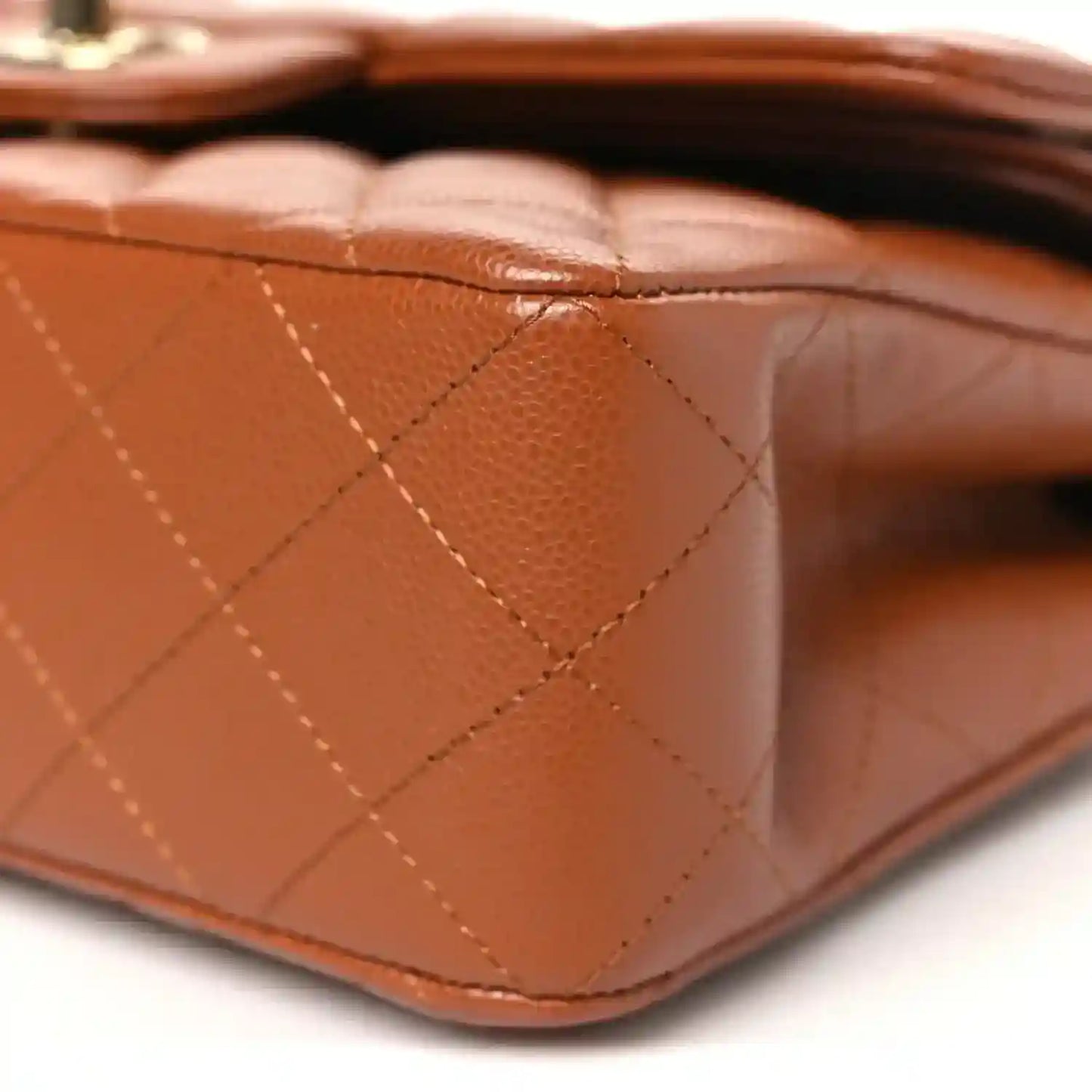 Caramel quilted leather base corner of a small double flap bag with seam detail