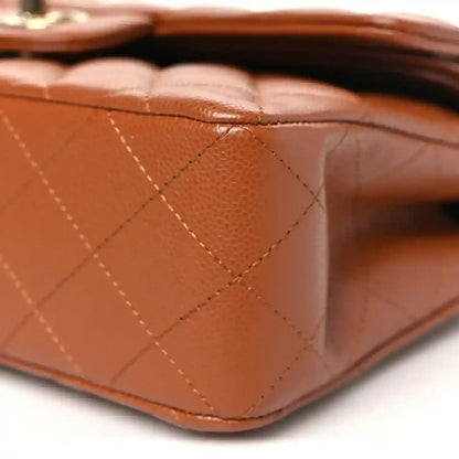 Caramel quilted leather base corner of a small double flap bag with seam detail