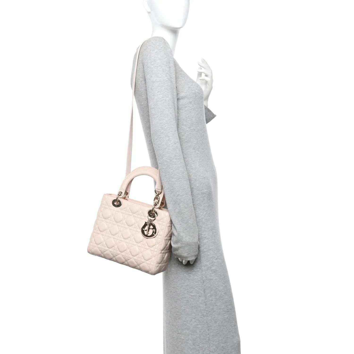 Powder pink quilted handbag with top handles and small charm detail on strap.