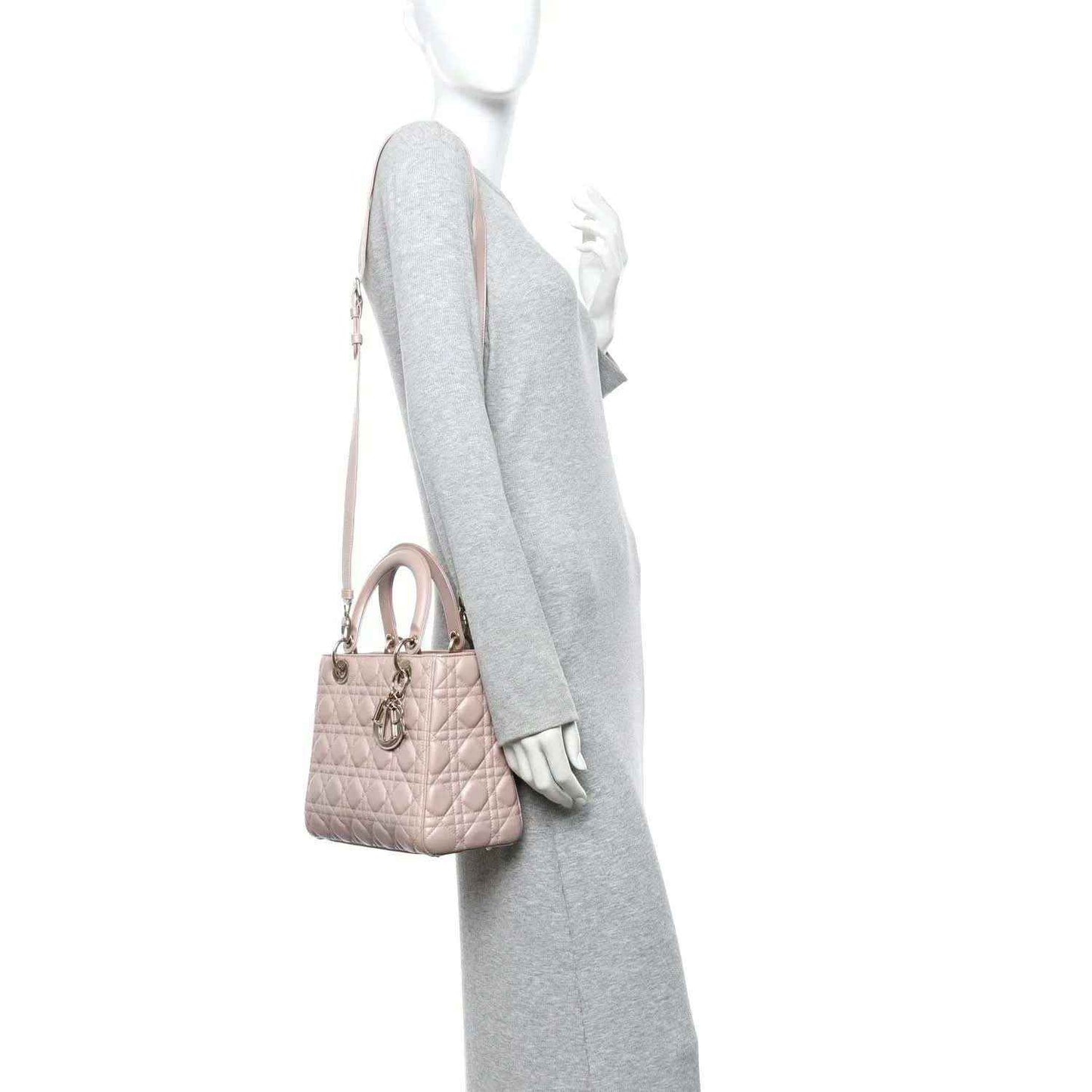 Light pink quilted handbag with top handle and detachable shoulder strap, worn on model