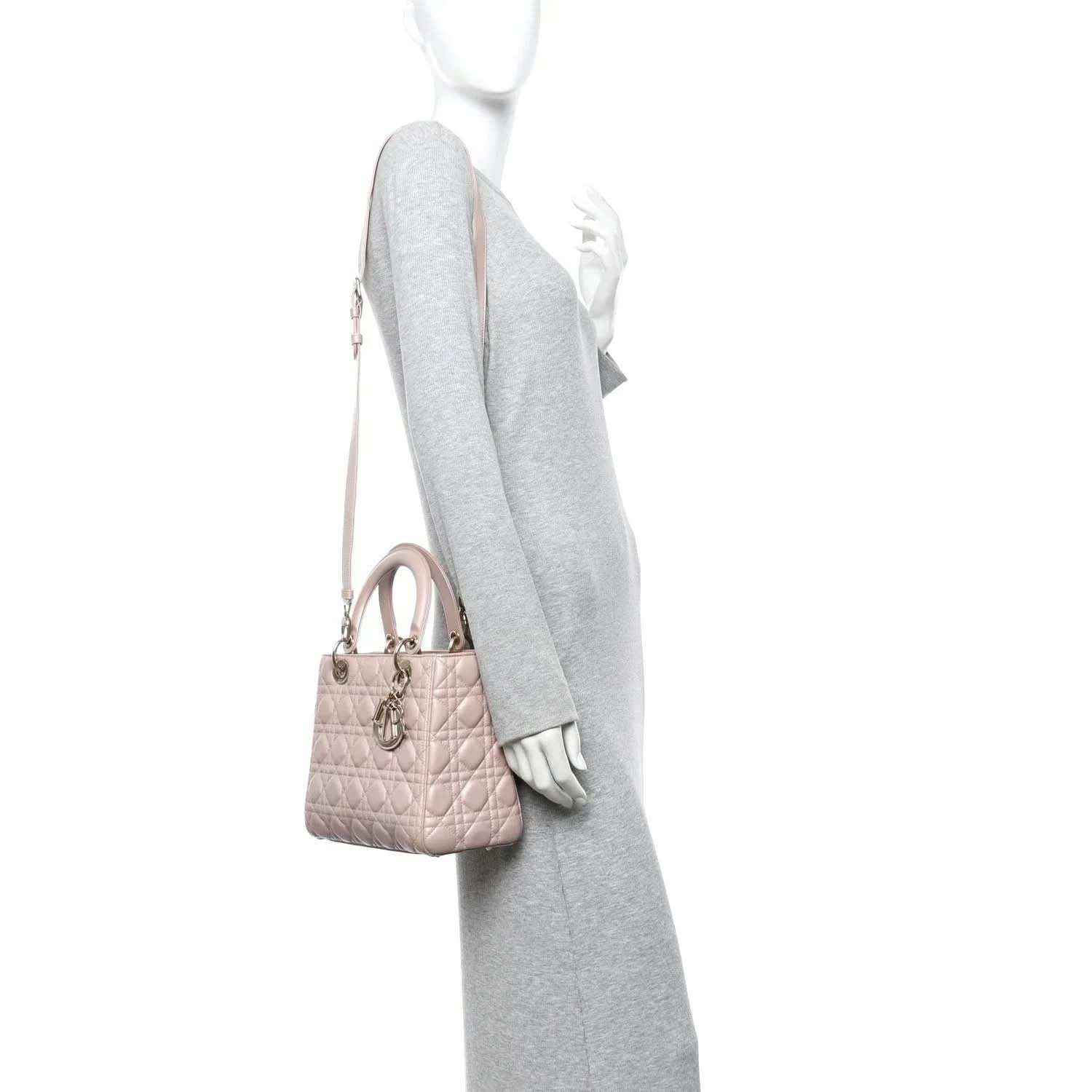 Light pink quilted handbag with top handle and detachable shoulder strap, worn on model
