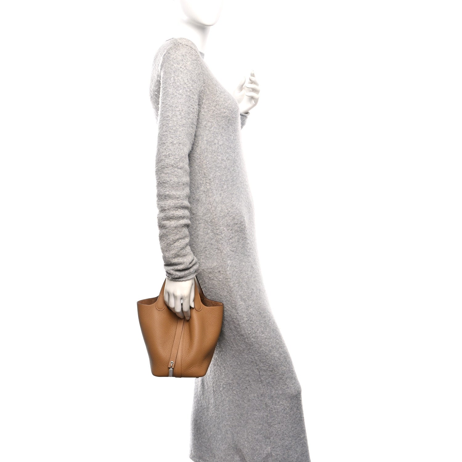 Tan leather mini tote bag held by a person, with top handles and silver clasp.