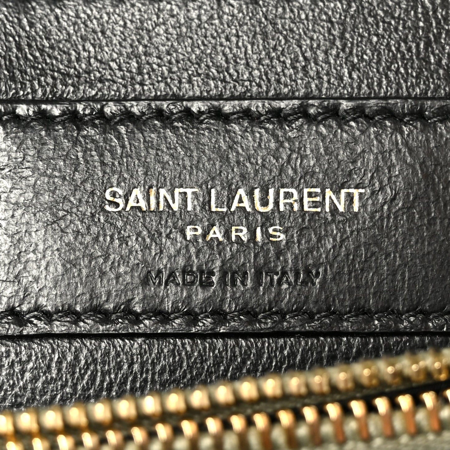 Black leather label on bag interior with “SAINT LAURENT PARIS” text and stitching