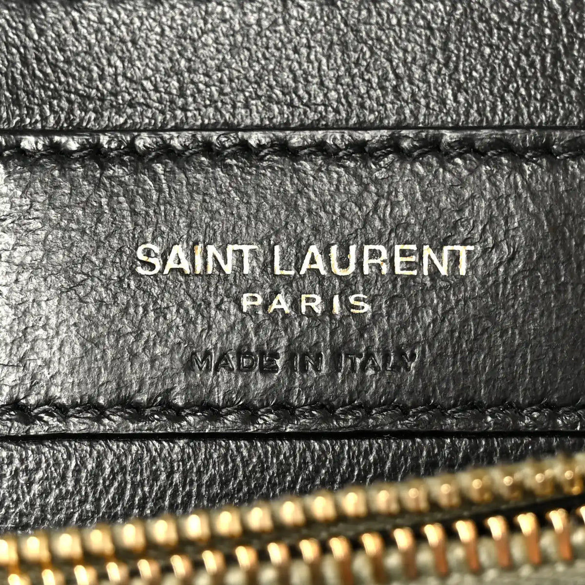 Black leather label on bag interior with “SAINT LAURENT PARIS” text and stitching