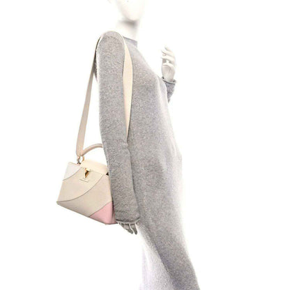 Beige handbag side view with short handle, shoulder strap, textured leather