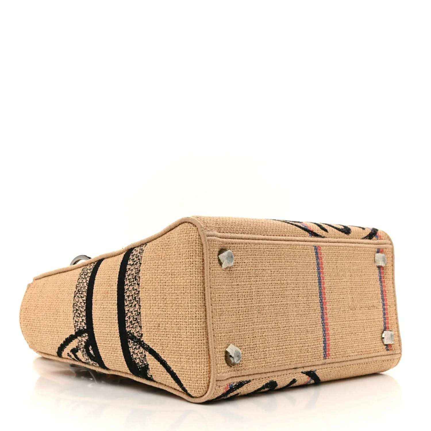 Jute canvas handbag with side stripes and front pocket, silver studs visible.