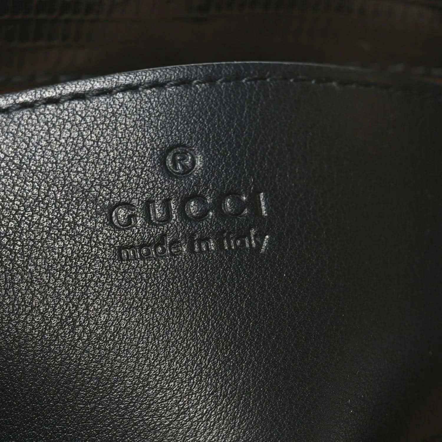 Gucci logo embossed on black leather handbag interior lining.
