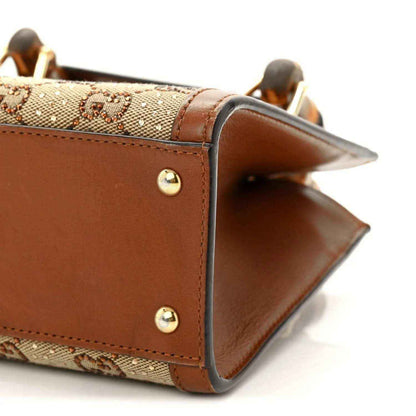 Gucci mini tote bag corner close-up with gold-tone studs and brown leather trim.