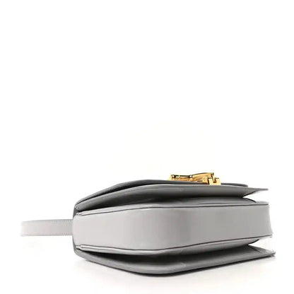 Light grey small shoulder bag side view with gold-tone top clasp and structured silhouette