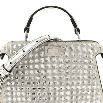 Silver crystal satchel front with top handle, flap clasp, and studded texture