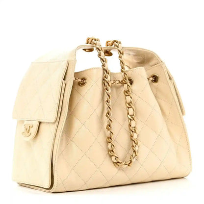 Light beige quilted small handbag with side flap pocket and gold chain shoulder strap