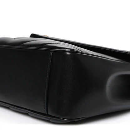 Black quilted leather shoulder bag, side view with top handle and stitching
