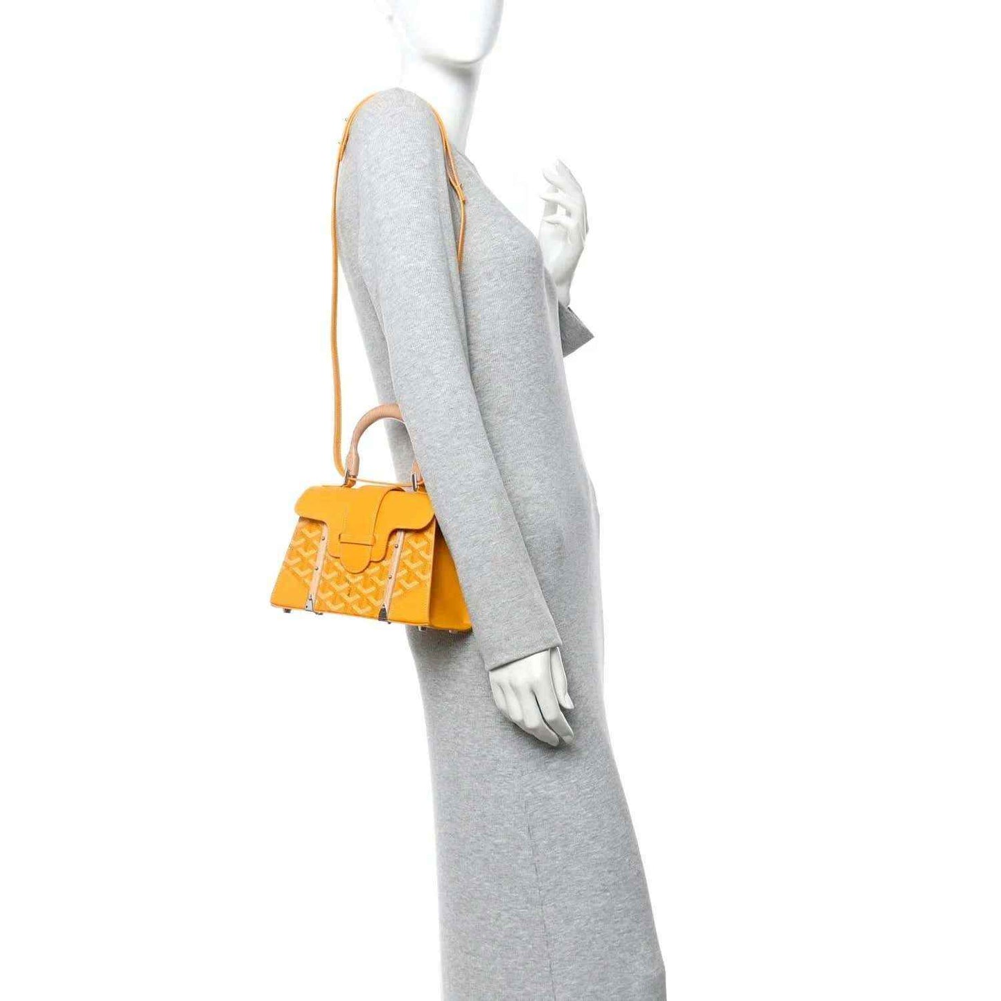 Yellow canvas mini handbag worn crossbody with shoulder strap and short top handles.
