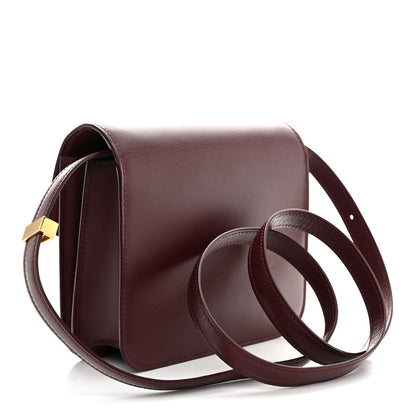 Burgundy leather box flap bag with curved shoulder strap and gold-tone clasp hardware.