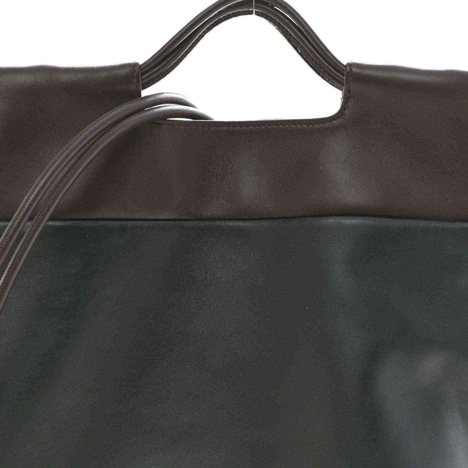Close-up of black leather tote bag top edge and handle openings.